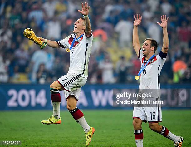 Bastian Schweinsteiger of Germany and Philipp Lahm of Germany celebrate with the World Cup trophy after defeating Argentina 1-0 in extra time during...