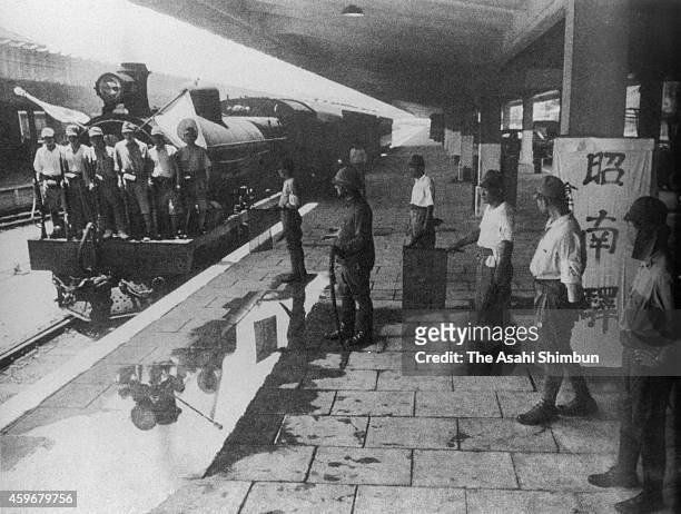 Train hoisting the Japanese national flags apporaches to a platform of 'Shonan' station after the fall of Singapore and renamed to Shonan circa...