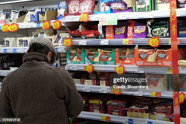 Customer looks at a blocks of cheddar cheese displayed for sale in the chilled aisle of an Asda supermarket, operated by Wal-Mart Stores Inc., in the...