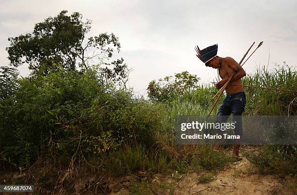 Member of the Munduruku indigenous tribe holds a bow and arrows along the Tapajos River during a "Caravan of Resistance'" protest by indigenous...