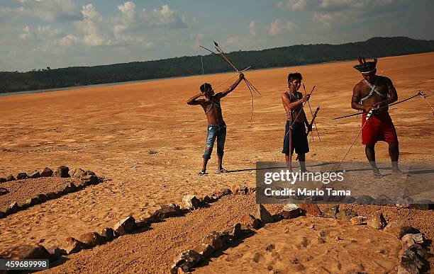 Members of the Munduruku indigenous tribe prepare to protest by symbolically aiming arrows on the banks of the Tapajos River against plans to...