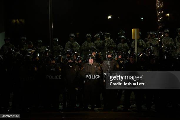 Demonstrator protesting the shooting death of Michael Brown shines a spot light on a group of police officers and National Guard troops outside of...