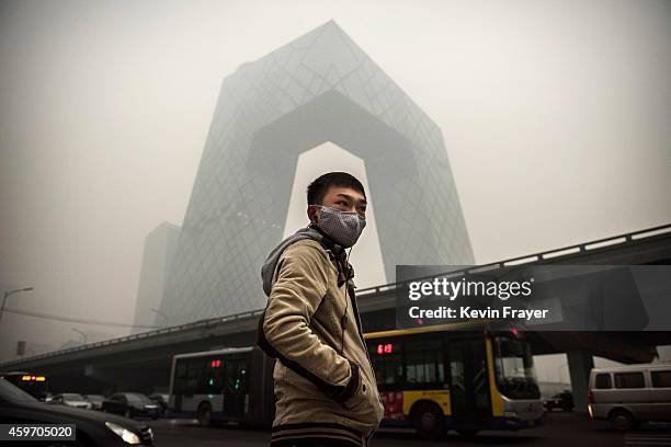 Chinese man wears a mask as he waits to cross the road near the CCTV building during heavy smog on November 29, 2014 in Beijing, China. United States...