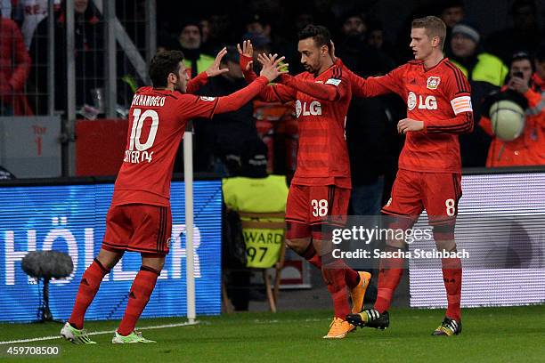 Karim Bellarabi of Leverkusen celebrates with team mate Hakan Calhanoglu and Lars Bender after scoring his team's first goal during the Bundesliga...