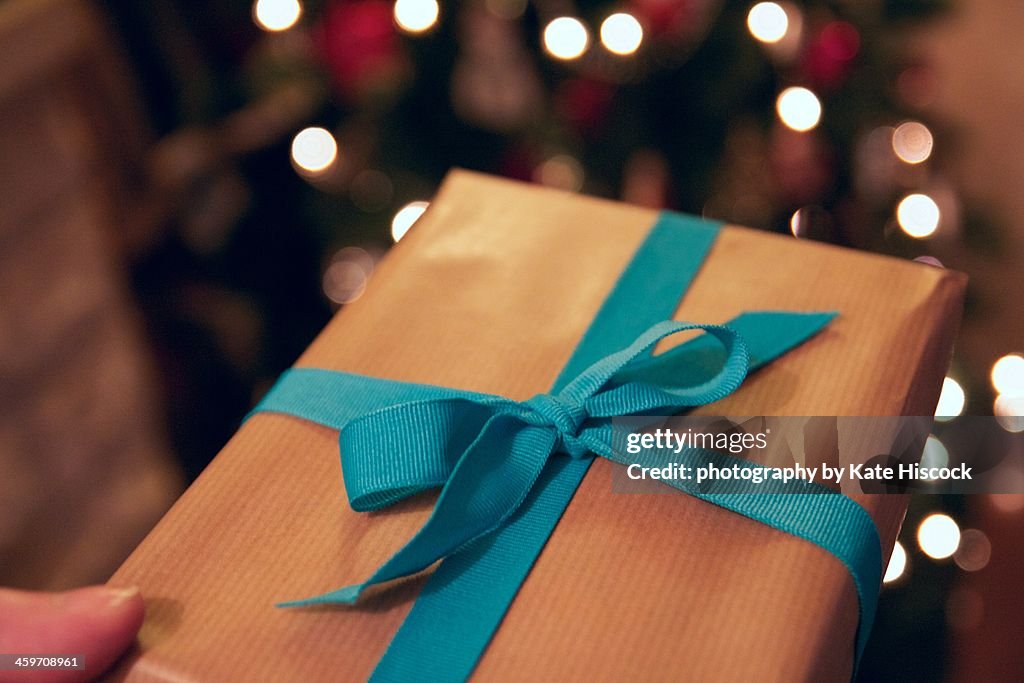 A holiday gift wrapped in brown paper and ribbon