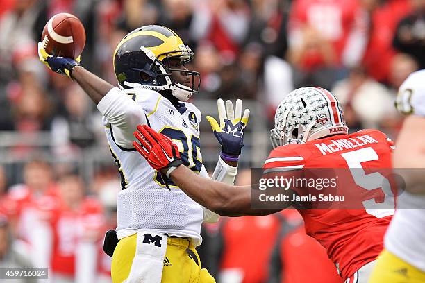 Quarterback Devin Gardner of the Michigan Wolverines tosses a 12-yard touchdown pass as he is rushed by Raekwon McMillan of the Ohio State Buckeyes...