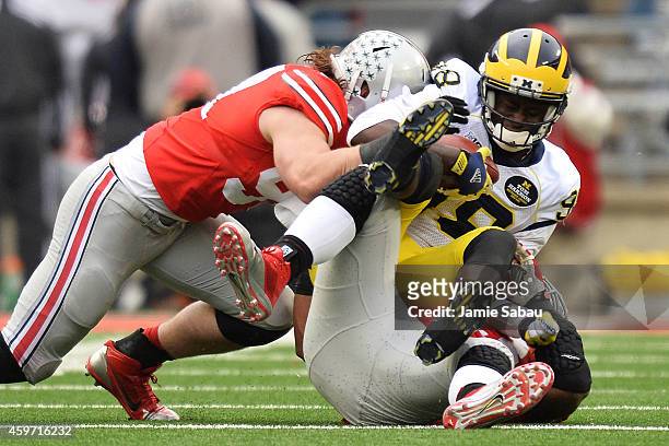 Quarterback Devin Gardner of the Michigan Wolverines is sacked for a 29-yard loss by Michael Bennett of the Ohio State Buckeyes and Joey Bosa of the...