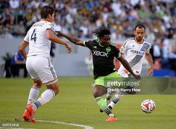 Obafemi Martins of Seattle Sounders FC attempts a shot between Omar Gonzalez and Juninho of Los Angeles Galaxy during the Western Conference Final at...