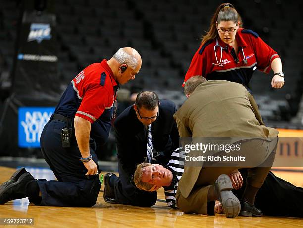 Referee Rick Crawford is attended to by EMS workers after collapsing on the floor just after the tip off of the consolation game between the La Salle...