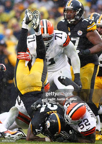 Le'Veon Bell of the Pittsburgh Steelers is up ended while rushing against the Cleveland Browns during the game on December 29, 2013 at Heinz Field in...