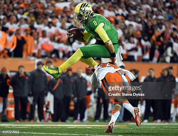 Quarterback Marcus Mariota of the Oregon Ducks hurdles safety Justin Strong of the Oregon State Beavers during the first quarter of the game at Reser...