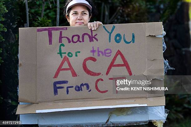Woman holding a sign in support of the Affordable Care Act is seen as US President Barack Obama's motorcade returns to his vacation compound from the...