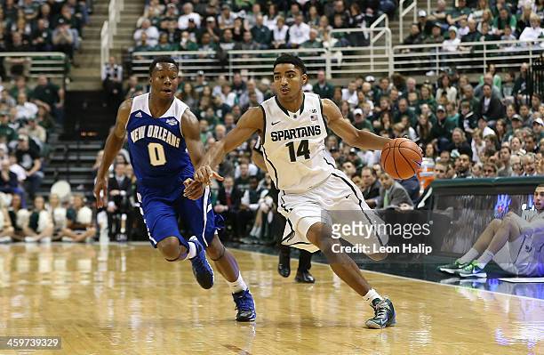 Gary Harris of the Michigan State Spartans drives the ball to the basketball as Tradarri McPhearson of the New Orleans Privateers defends during the...