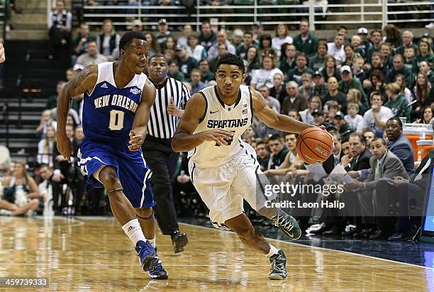 Gary Harris of the Michigan State Spartans drives the ball to the basketball as Tradarri McPhearson of the New Orleans Privateers defends during the...