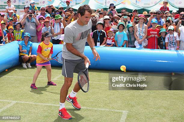 Roger Federer of Switzerland plays mini tennis with junior fans during day two of the 2014 Brisbane International at Queensland Tennis Centre on...