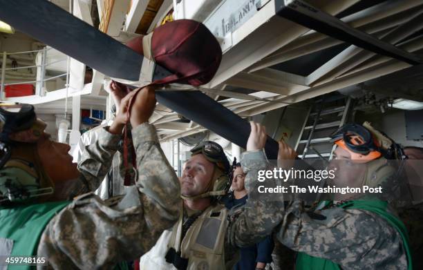 Army personnel use some tape to secure some padding to prevent damage to the OH-58 Kiowa Warrior helicopter blades on board the USS Lake Erie CG-70 a...