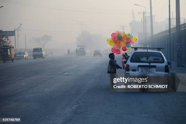 In this photograph taken on December 27 Bashir, an Afghan boy who says he is five years old, negotiates a sale of balloons with a customer along a...