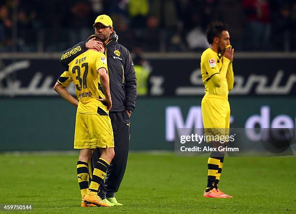 Erik Durm and Pierre-Emerick Aubameyang of Borussia Dortmund look dejected while head coach Juergen Klopp hugs Durm after the Bundesliga match...