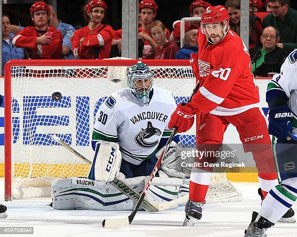 Drew Miller of the Detroit Red Wings tries to tip the puck as his brother and goalie Ryan Miller of the Vancouver Canucks tries to locate it during a...