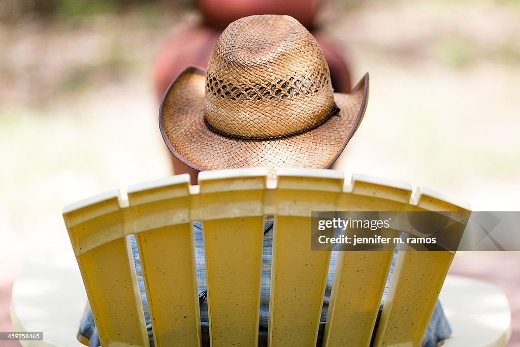 Straw cowboy hat on a man in a yellow lawn chair
