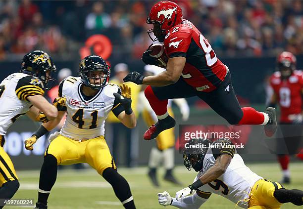 Nik Lewis of the Calgary Stampeders leaps open Brandon Stewart and into Erik Harris and Craig Butler of the Hamilton Tiger-Cats during the 102nd Grey...