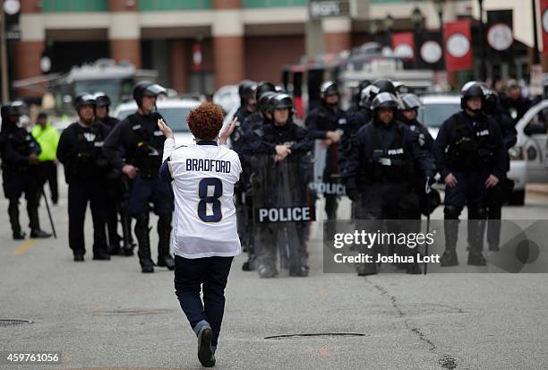 Football fan applauds police officers as they watch as demonstrators protest the shooting death of Michael Brown outside the Edward Jones Dome...