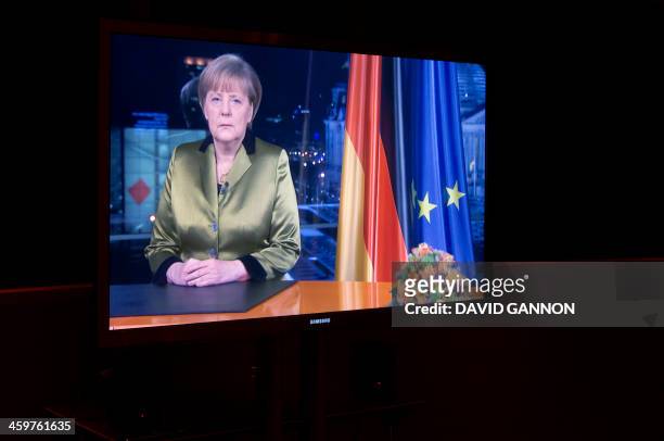 The recording of German Chancellor Angela Merkel's annual New Year's speech is seen on a TV screen in a room at the Chancellery in Berlin on December...