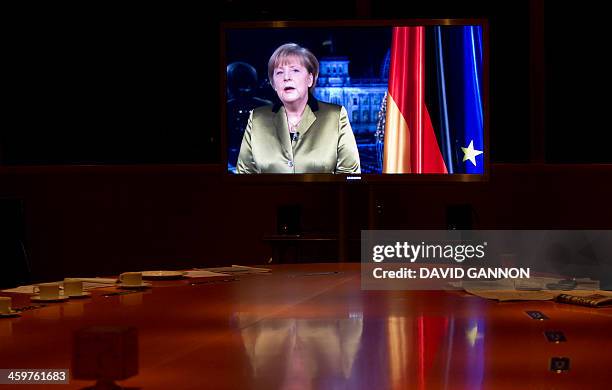 Technicians watch the recording of German Chancellor Angela Merkel's annual New Year's speech on a TV screen in a room at the Chancellery in Berlin...