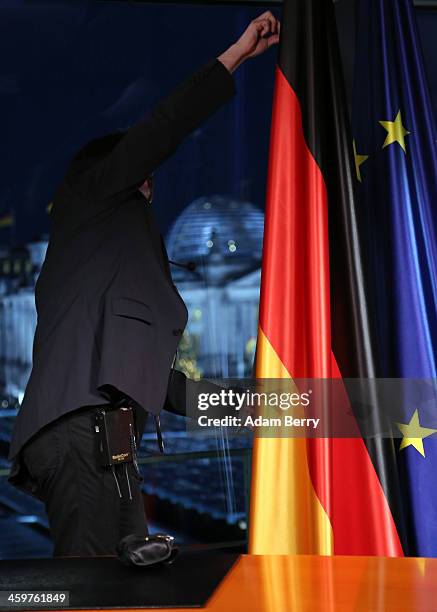 Technician adjusts a German national flag prior to the recording of German Chancellor Angela Merkel's New Year's television address to the nation at...