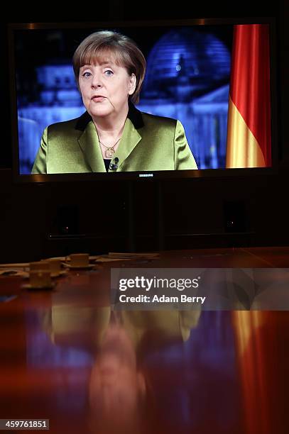 German Chancellor Angela Merkel is seen speaking on a video monitor as she gives her New Year's television address to the nation at the federal...