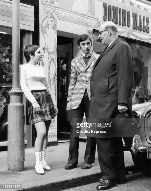 Sir William Fiske talks to a boutique assistant in front of store on Carnaby Street in London, England.