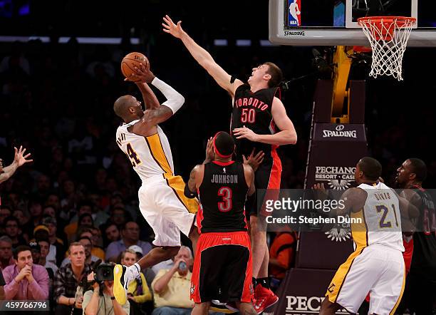 Kobe Bryant of the Los Angeles Lakers shoots over Tyler Hansbrough and James Johnson of the Toronto Raptors at Staples Center on November 30, 2014 in...