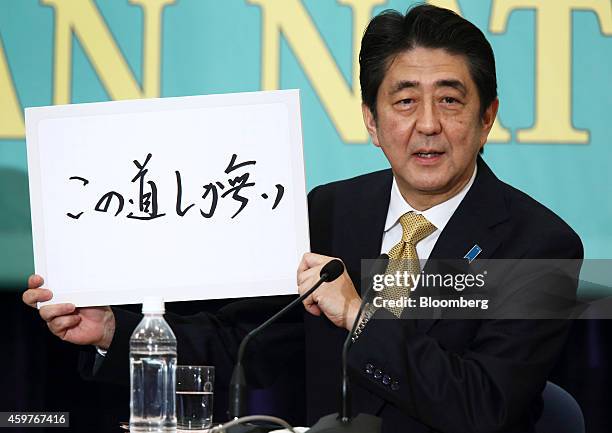 Shinzo Abe, Japan's prime minister and president of the Liberal Democratic Party , holds a sign featuring a slogan as he speaks during a debate with...