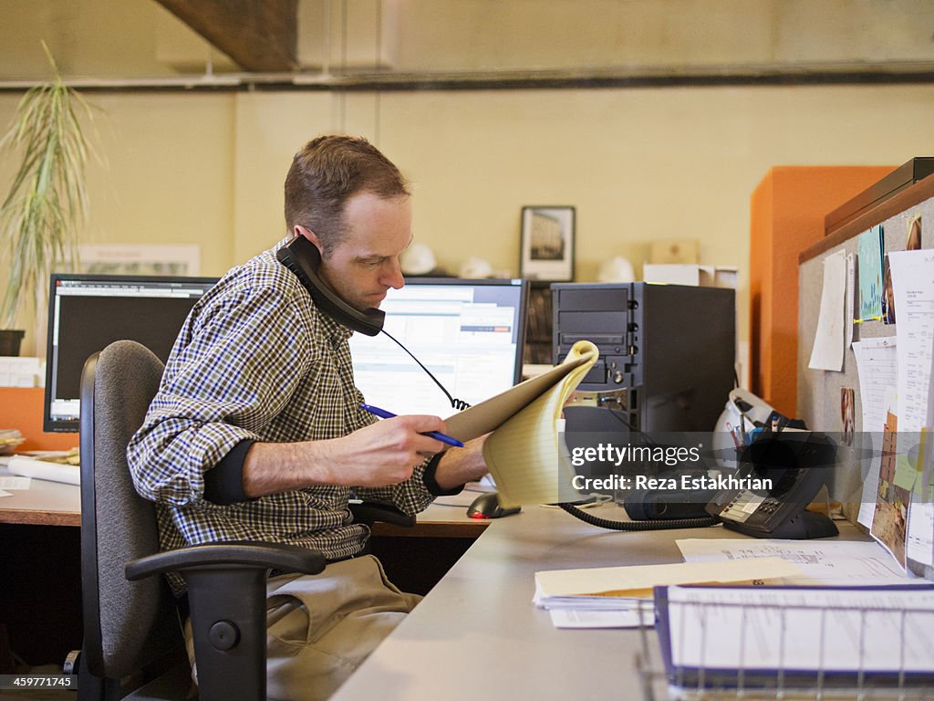 Businessman checks notes while on the phone