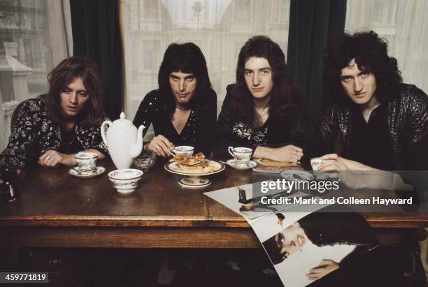 English rock group Queen posed at a dining table in lead singer Freddie Mercury's flat, Holland Road, West Kensington, London in early 1974. Left to...