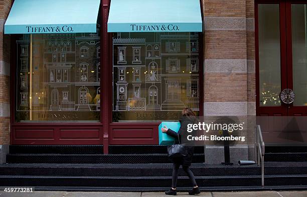 Pedestrian carries a box while looking in the window of a Tiffany & Co. Store in the Soho neighborhood of New York, U.S., on Monday, Dec. 30, 2013....