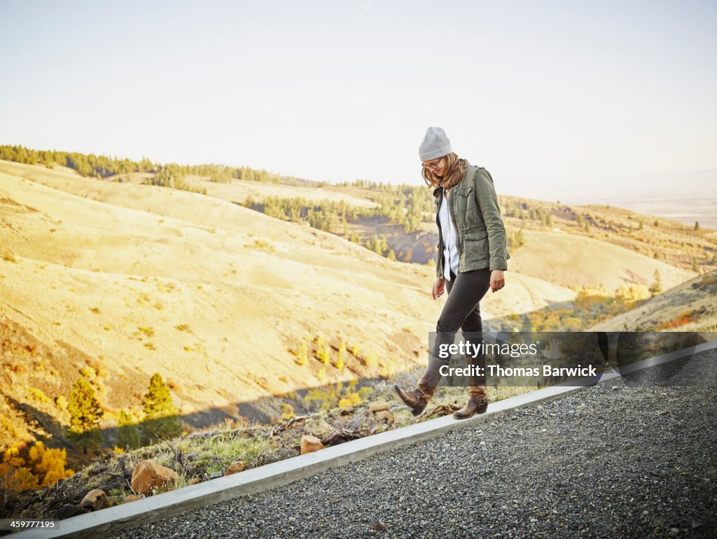 Woman walking along concrete wall on hillside