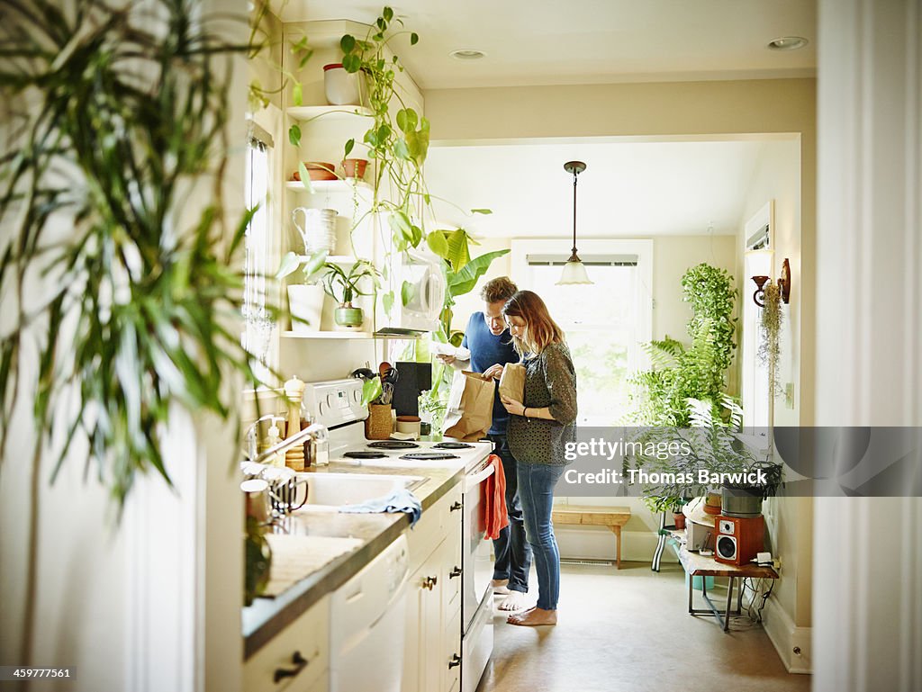 Couple unpacking groceries in kitchen of home