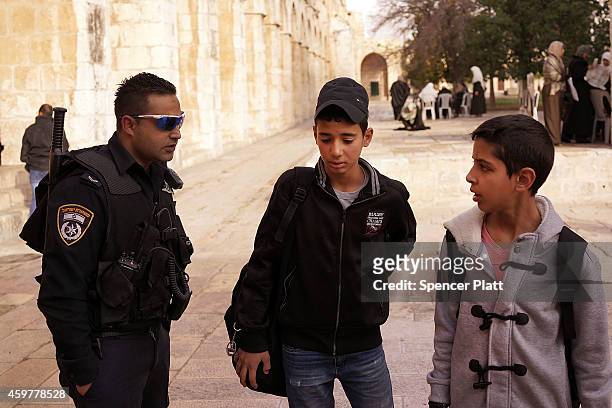 An Israeli police officer questions young Arabs near the Dome of the Rock at the Al-Aqsa mosque compound in the Old City on December 01, 2014 in...