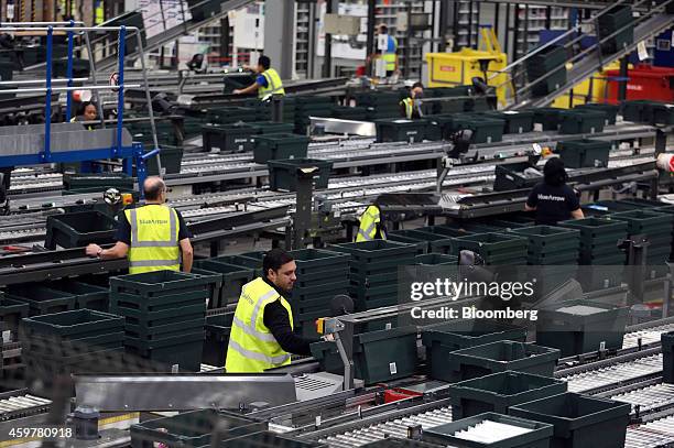 Workers wear Blue Arrow recruitment agency branded high visibility saftey jackets as they sort customer "click and collect" orders into crates...