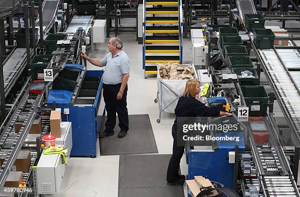 Workers sort goods into crates ahead of processing customer orders at the John Lewis Plc semi-automated distribution centre in Milton Keynes, U.K.,...