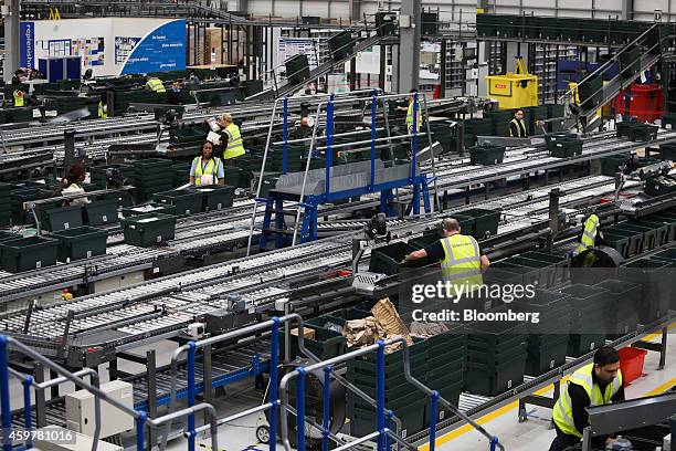 Workers wear Blue Arrow recruitment agency branded high visibility safety jackets as they sort customer "click and collect" orders into crates...