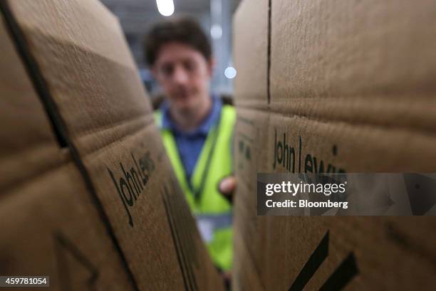 Worker selects a John Lewis branded cardboard box before packaging a customer's order at the John Lewis Plc semi-automated distribution centre in...