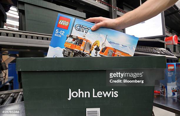 Worker selects a box of Lego from a crate as he processes a customer's order at the John Lewis Plc semi-automated distribution centre in Milton...