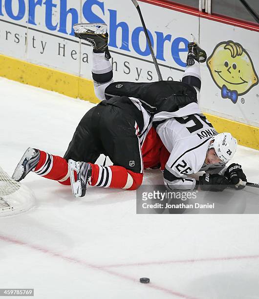 Slava Voynov of the Los Angeles Kings falls over Michal Handzus of the Chicago Blackhawks as the puck slips away at the United Center on December 30,...