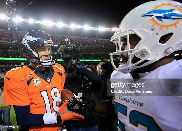 Quarterback Peyton Manning of the Denver Broncos greets outside linebacker Jelani Jenkins of the Miami Dolphins after the game at Sports Authority...