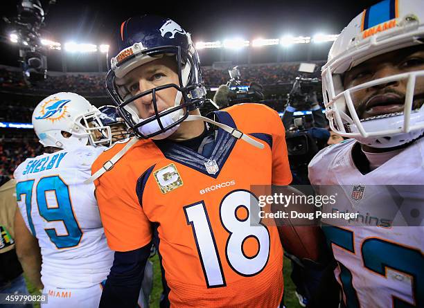 Quarterback Peyton Manning of the Denver Broncos and Derrick Shelby and outside linebacker Jelani Jenkins of the Miami Dolphins leave the field after...