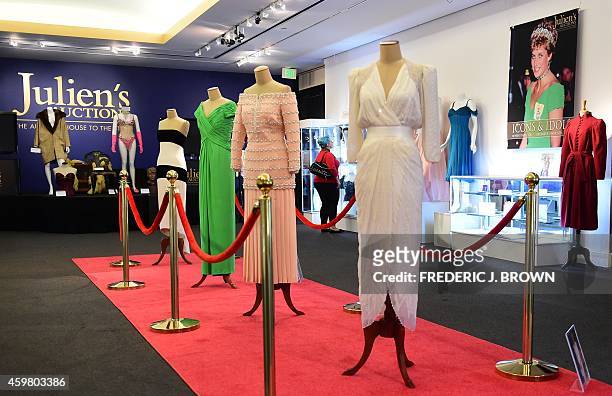 Five dresses worn by the late Princess Diana, four on a red carpet and one beside her poster, are displayed at Julien's Auction House in Beverly...