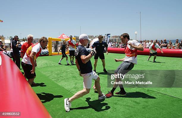 Robbie Slater tackles Adam Peacock during the all-stars match during the Fox Sports Asian Cup coverage launch at Bondi Beach on December 2, 2014 in...