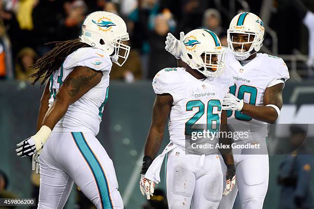 Lamar Miller of the Miami Dolphins celebrates with teammates Dallas Thomas and Dion Sims after scoring a 4 yard touchdown in the fourth quarter to...